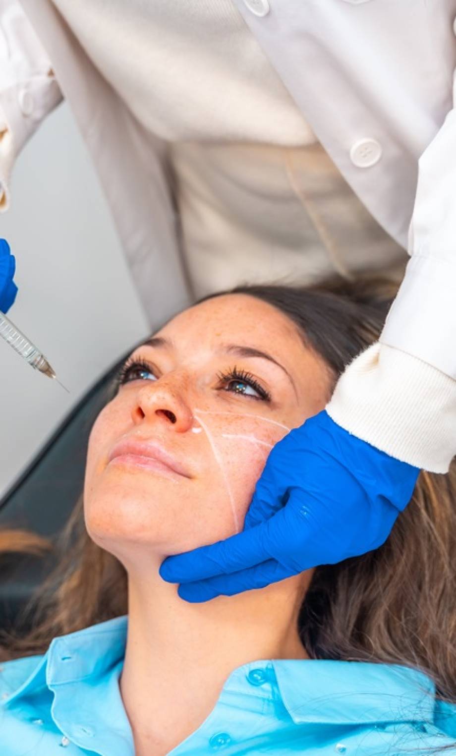 Elevated view of an unrecognizable female cosmetologist administering hyaluronic acid to the face of a woman in a beautician clinic